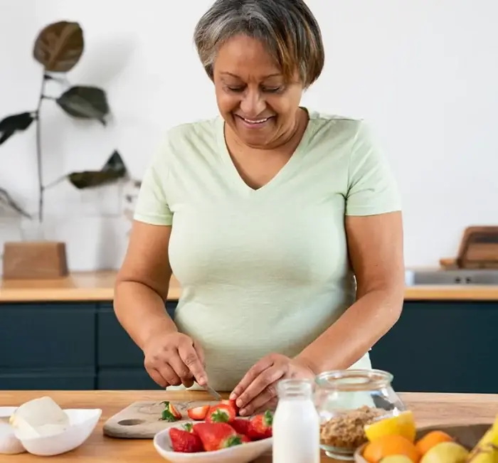A woman preparing fruit and yoghurt at a kitchen counter